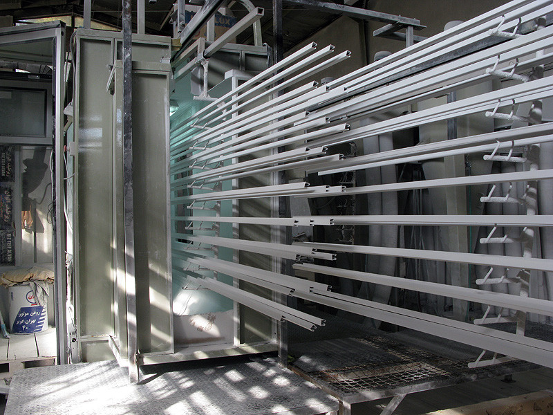 Perfiles de aluminio colgados en la cabina de esmaltado en polvo